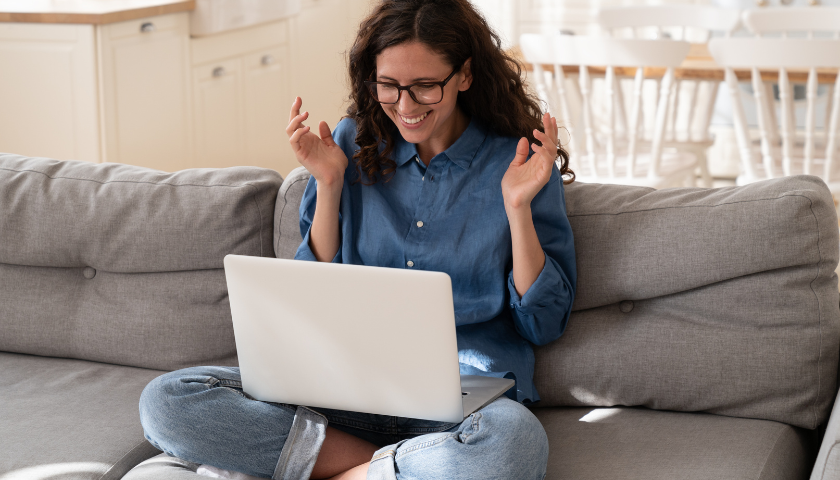 Young woman sitting on couch reading laptop.